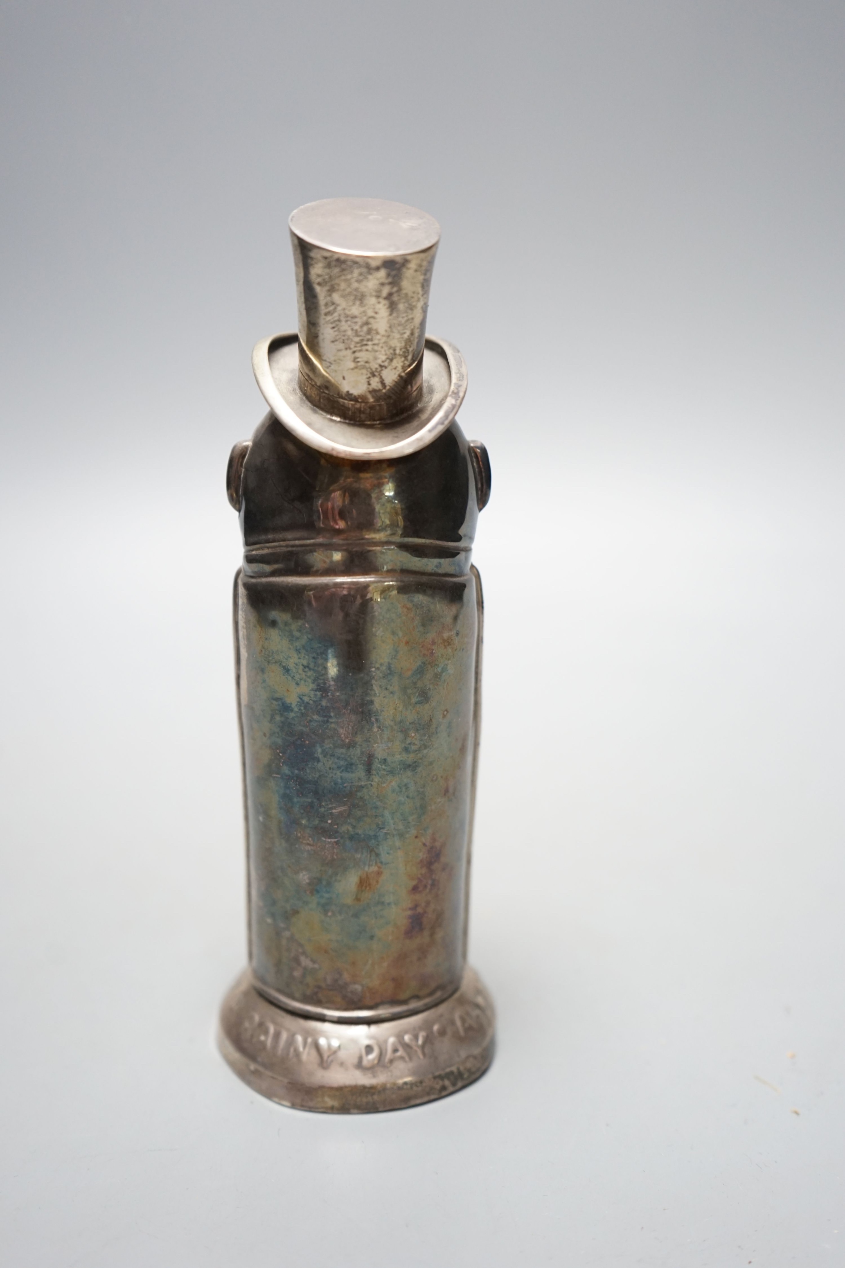 A George V silver novelty money box, embossed with a gentleman with top hat and umbrella, Birmingham, 1912, 16.9cm, inscribed 'Always be prepared for a rainy day', 107 grams.